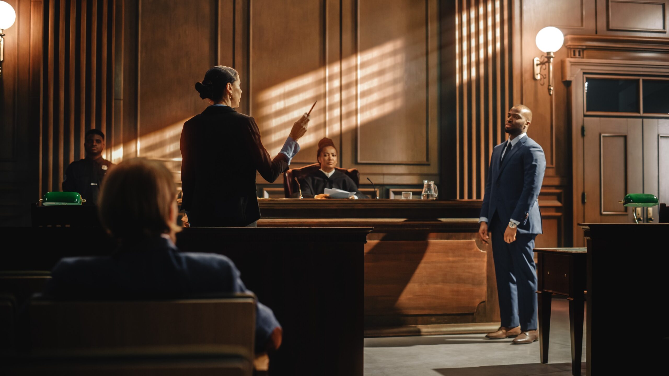 Lawyers presenting effective trial representation arguments in a courtroom during a trial, with one lawyer speaking to the judge and others seated at the table