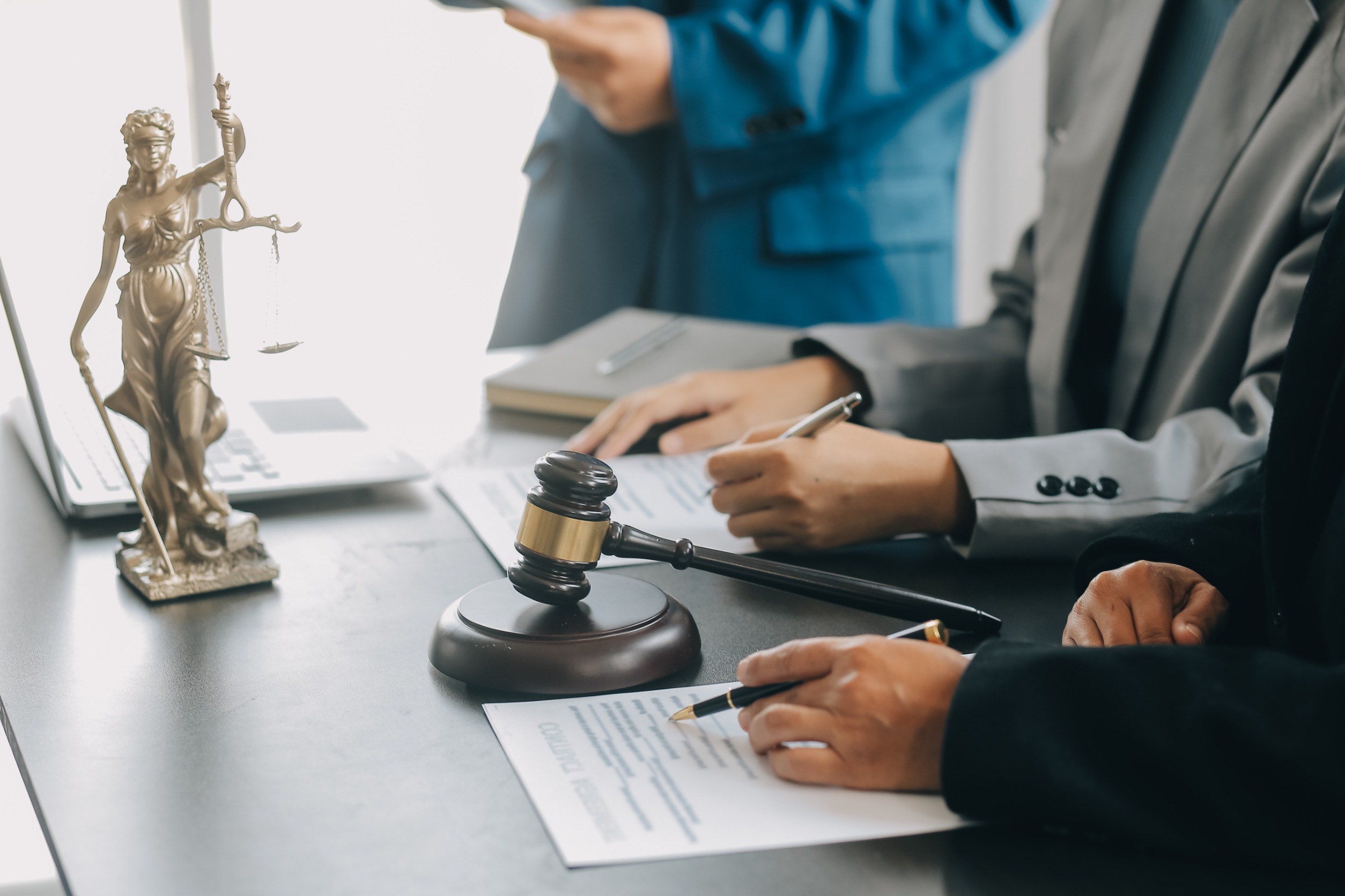 A lawyer’s hands writing notes on a legal document at a table.