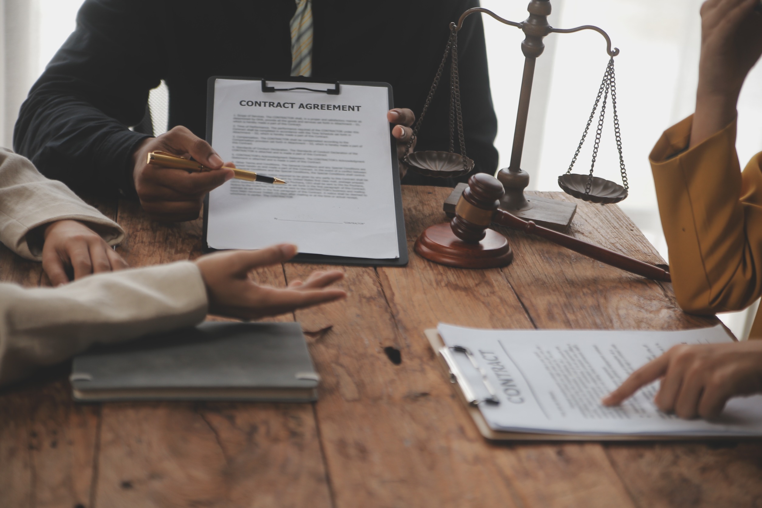 Lawyers discussing and reviewing contract agreements at a desk with legal documents, scales of justice, and a gavel, focusing on Accurate Legal Record management.