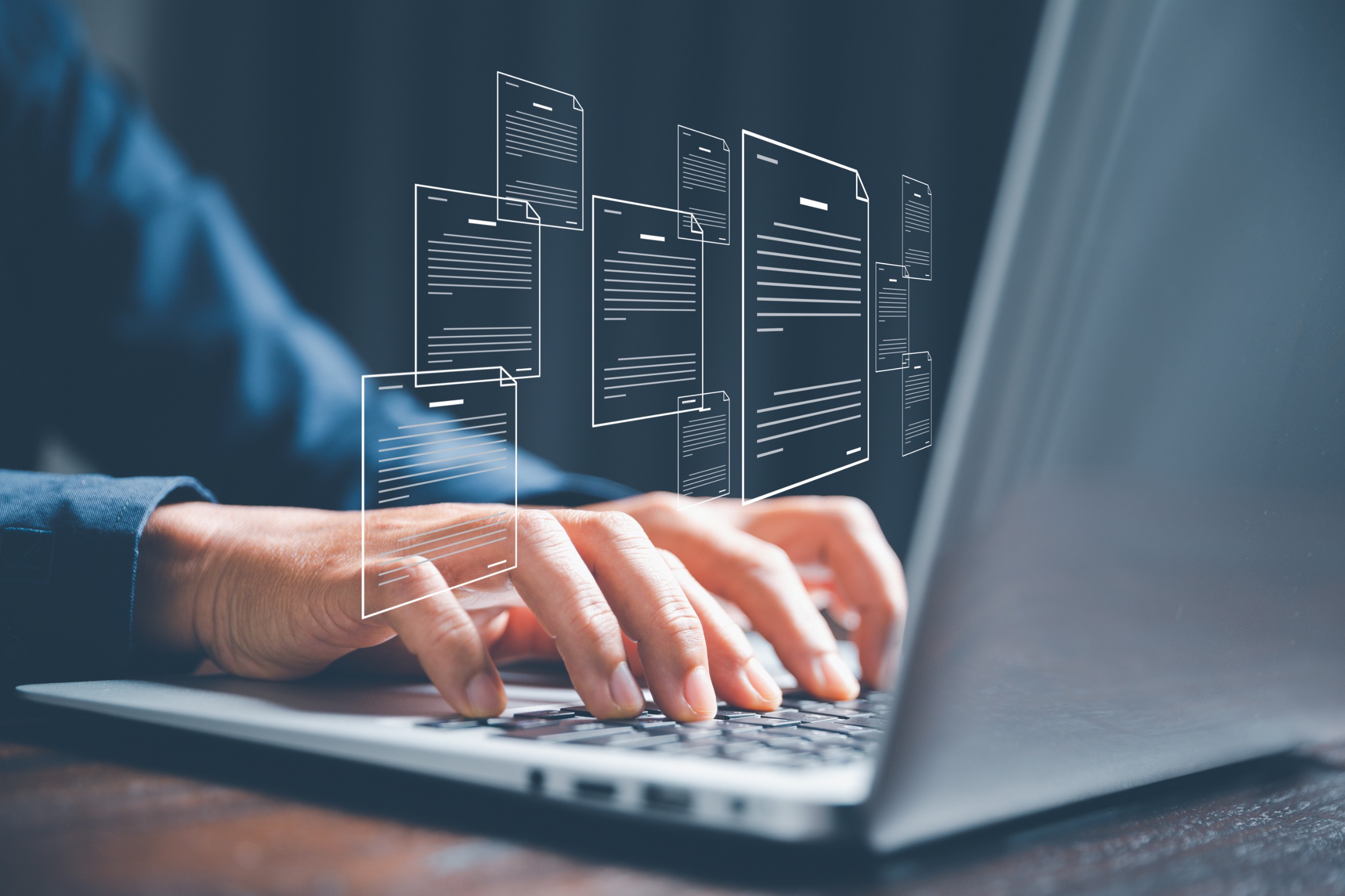 Close-up of hands typing on a laptop keyboard, with floating digital document icons superimposed above the screen, symbolizing digital file management or online documentation. The background is softly blurred, emphasizing the virtual elements.